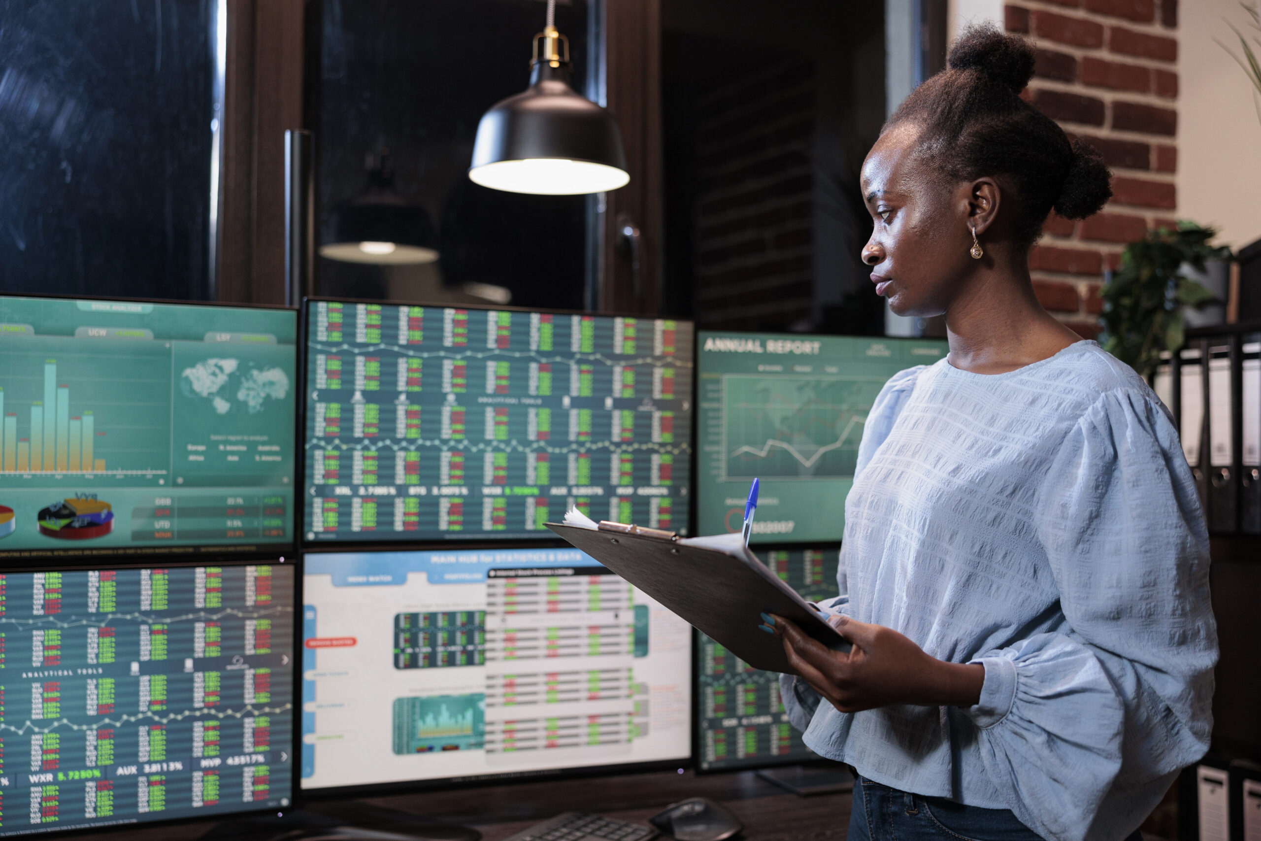 Forex stock market professional trader with clipboard standing in front of workstation while analyzing real time financial growth. Investment company employee analyzing trading index and trend charts.